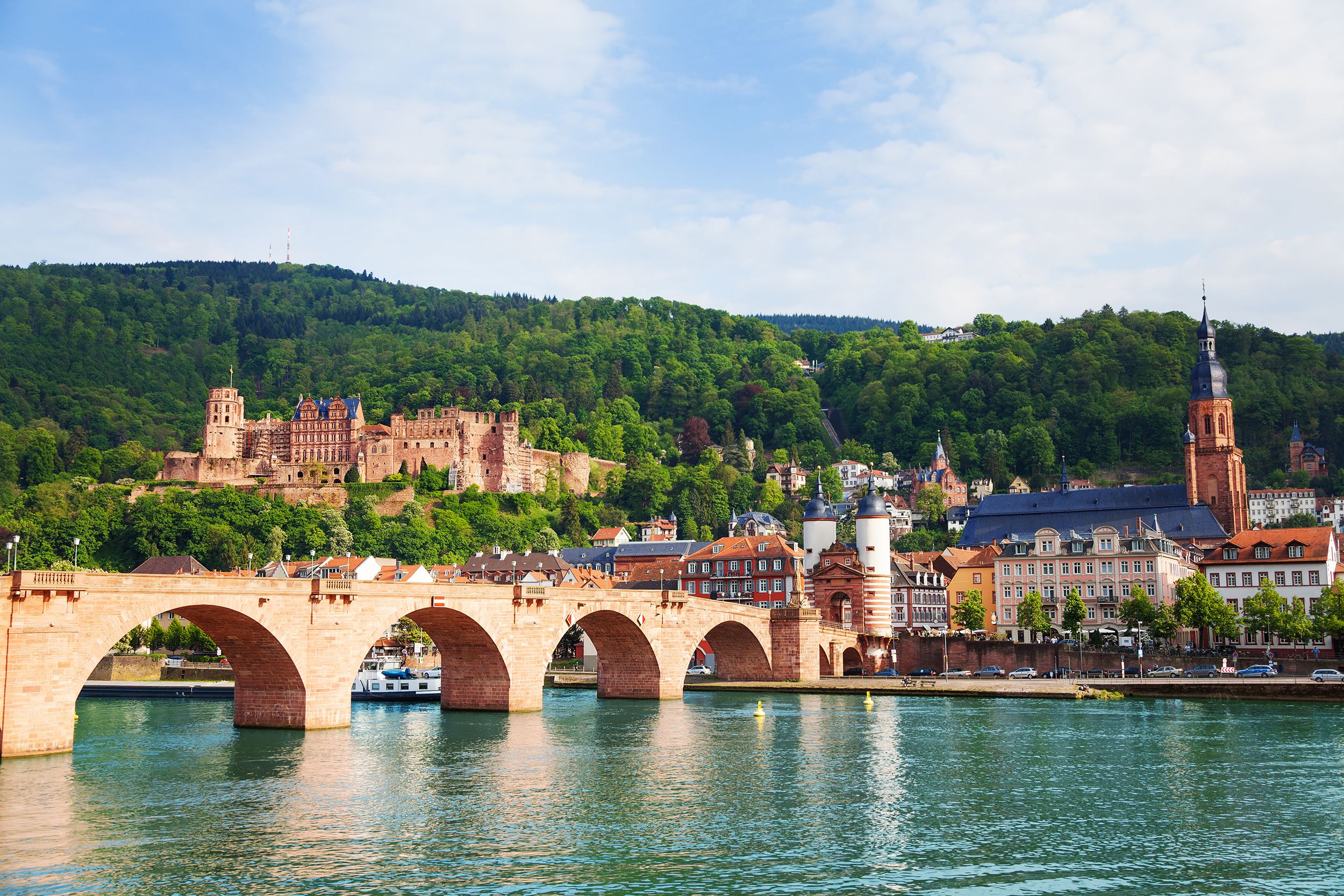 Blick auf die alte Mainbrücke in Heidelberg umgeben von Häusern einer Kirche und einer Burg