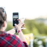 Frau macht Foto vom Weinglas vor der Landschaft