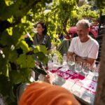 Mann unterhält sich zwischen den Weinbergen an einem Tisch mit mehreren leeren Weingläsern