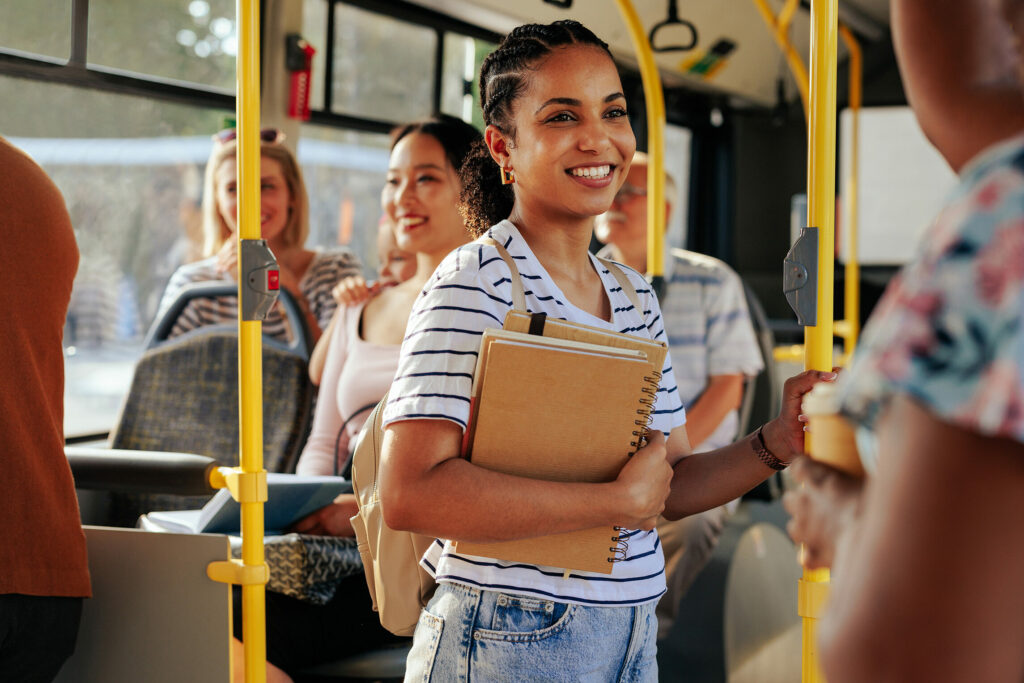 junge Frau steht lachend im Bus