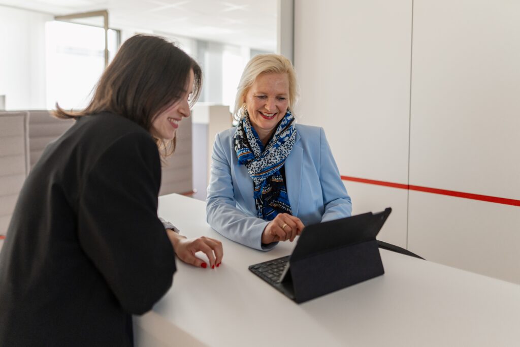 Zwei Mitarbeiterinnen mit IPad stehend am neuen Tisch am New Work Arbeitsplatz der WVV