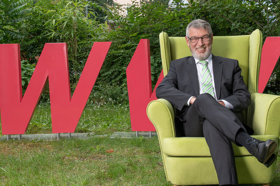 Der ehem. WVV-Geschäftsführer Thomas Schäfer sitzt in einem grünen Sessel vor dem WVV-Logo