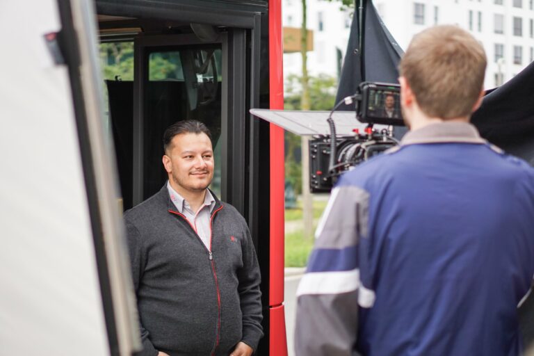 Busfahrer wird von Kameramann in der Türe des Busses gefilmt