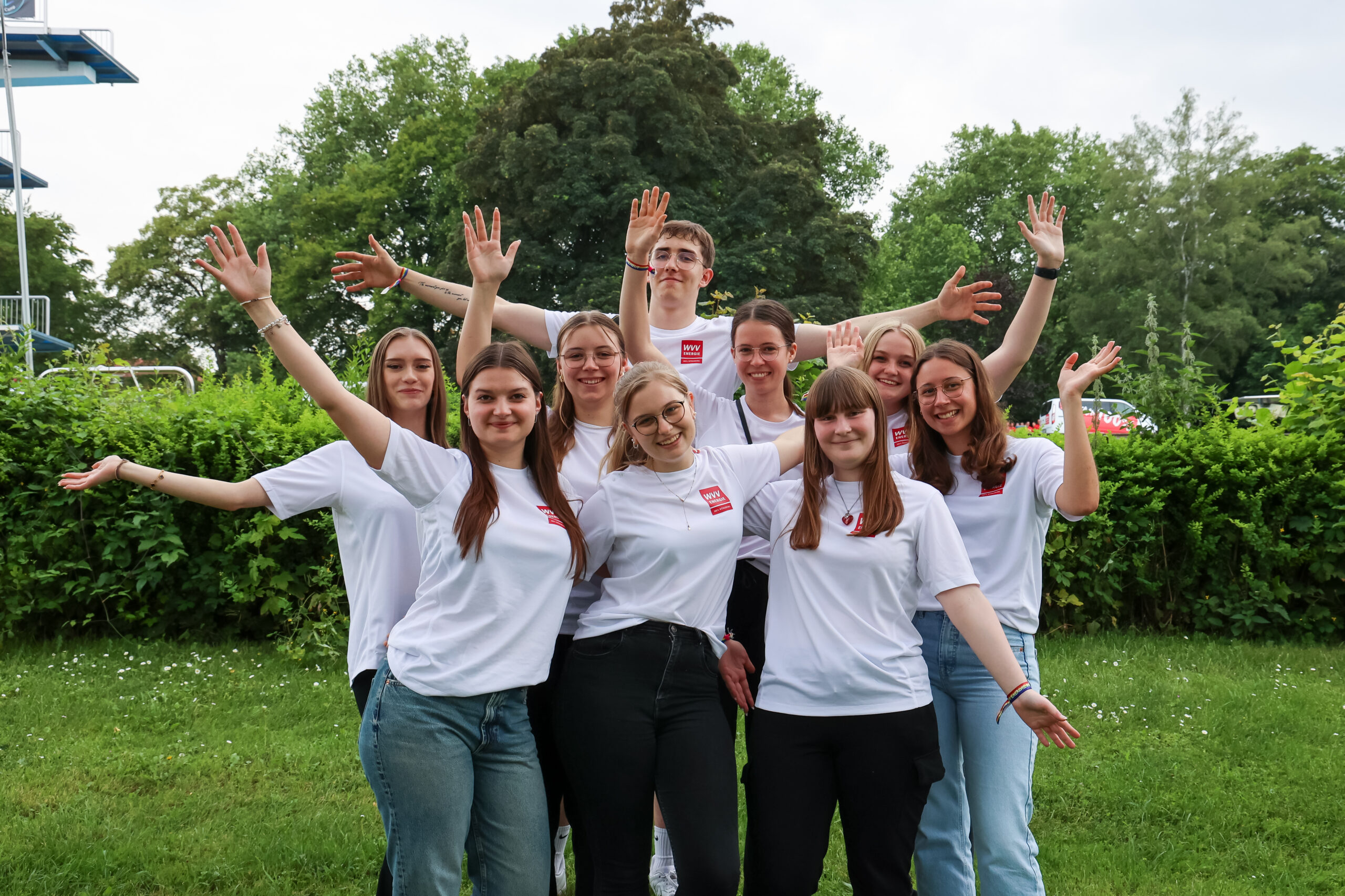 acht weibliche und ein männlicher Auszubildender mit freudig ausgestreckten Armen beim WVV Firmenlauf