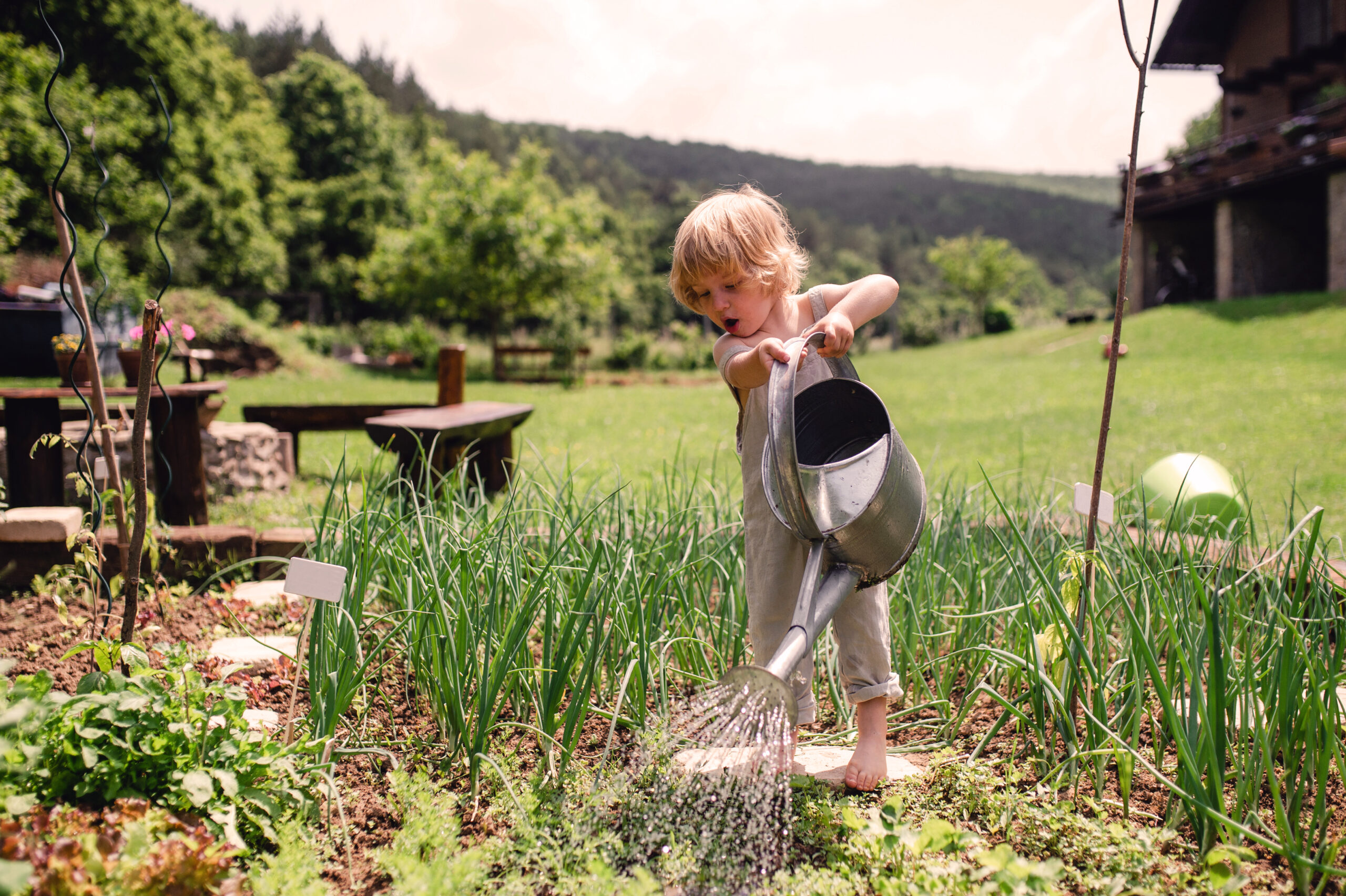 Kind mit Gießkanne auf grüner Wiese