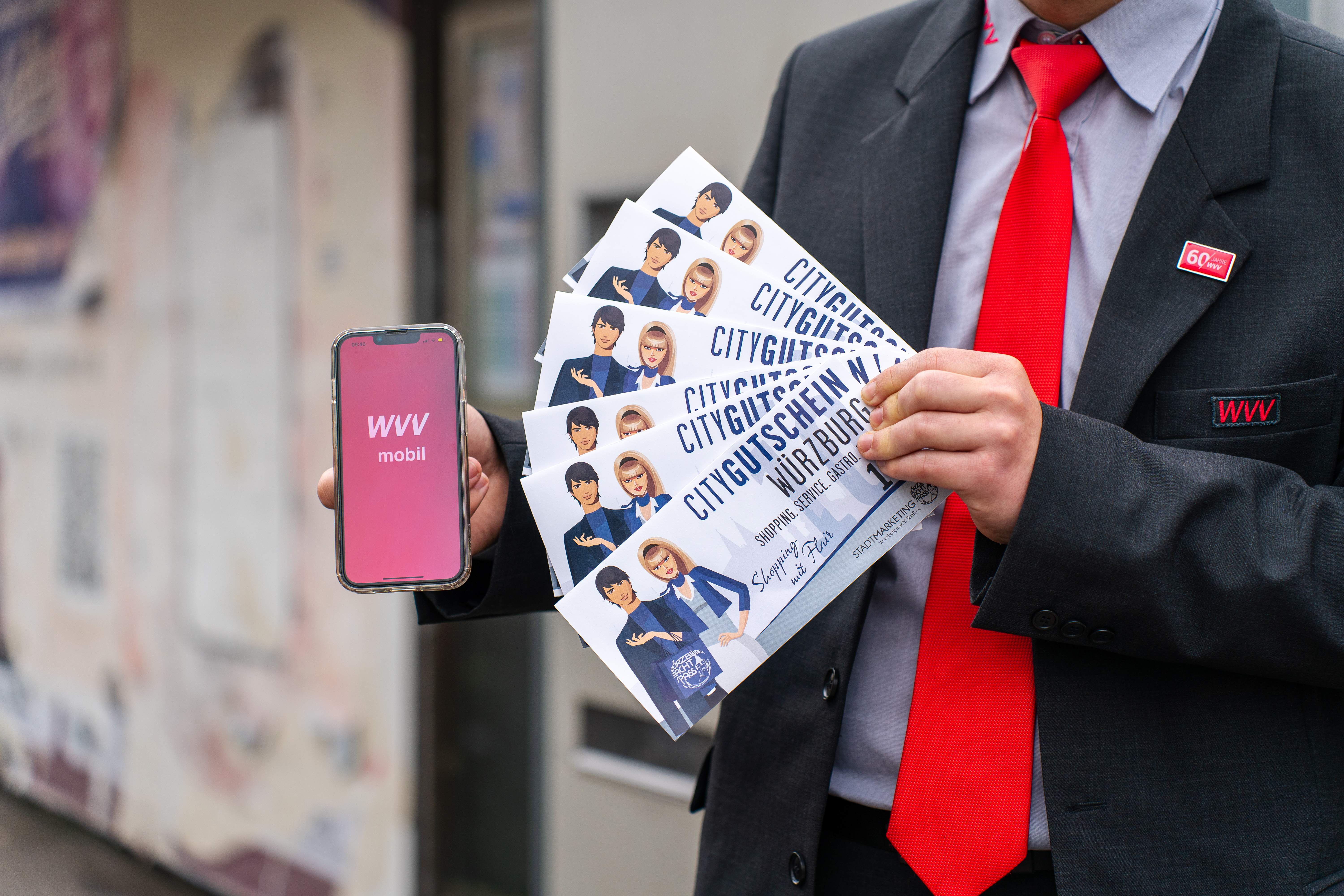 Ein WVV Schaffner zeigt die WVVmobil-App auf einem Smartphone vor.