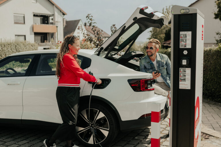 Frau und Mann sind glücklich beim E-Auto-Laden