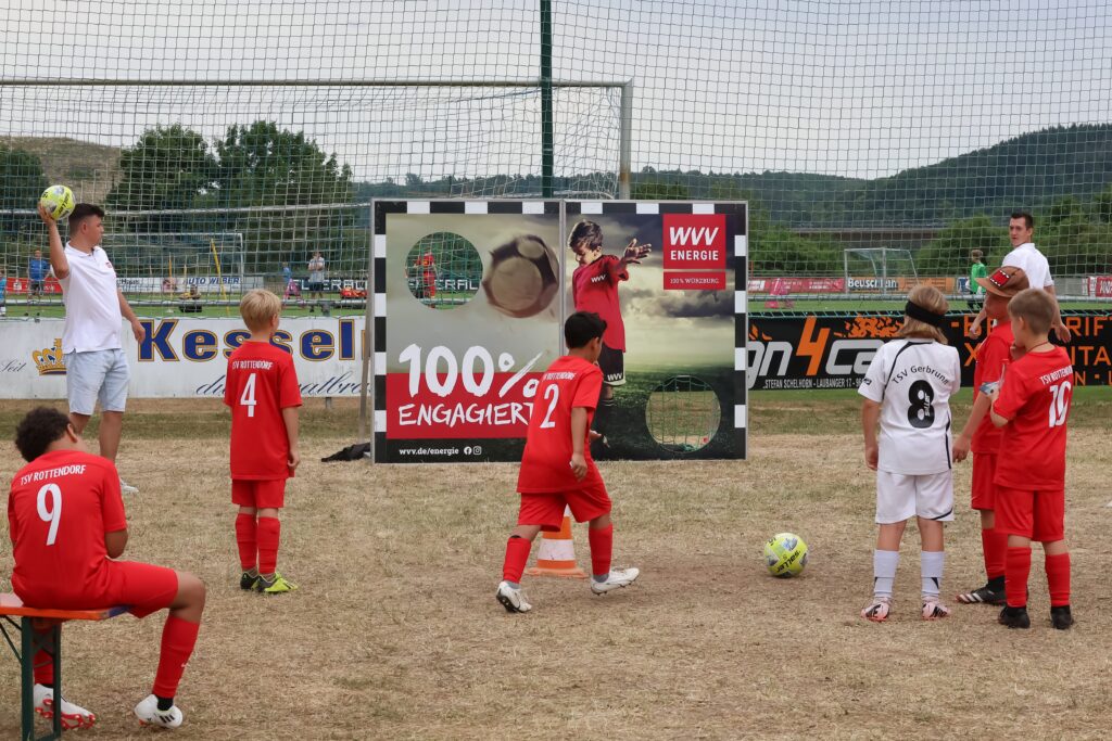 Jugendliche Fußballer stehen versammelt um die Torwand der WVV und versuchen ihr Glück